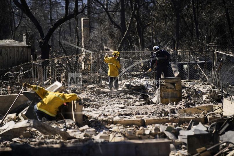 Uma equipa de busca e salvamento examina os destroços de uma casa destruída pelo incêndio de Eaton, terça-feira, 14 de janeiro de 2025, em Altadena, Califórnia. 