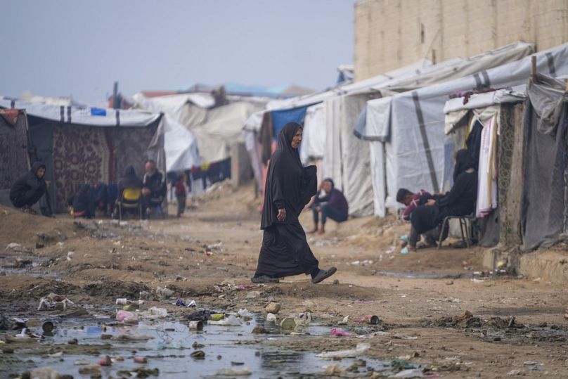 امرأة تسير في مخيم خيام للنازحين الفلسطينيين في دير البلح بوسط قطاع غزة.