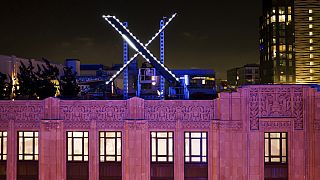 Workers install lighting on an "X" sign atop the company headquarters, formerly known as Twitter, in downtown San Francisco, July 28, 2023.