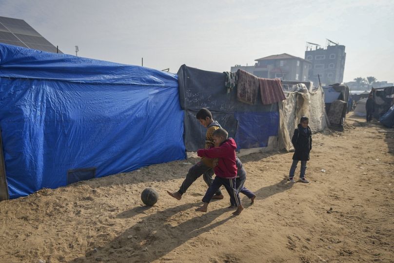 أطفال يلعبون كرة القدم في مخيم خيام للنازحين الفلسطينيين.