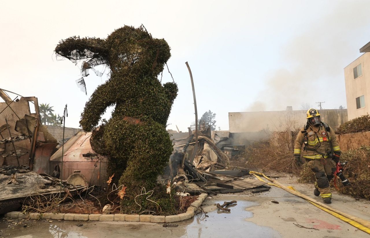 A firefighter walks past a charred bunny sculpture and debris at the destroyed Bunny Museum, Jan. 9, 2025, in Altadena, Calif.