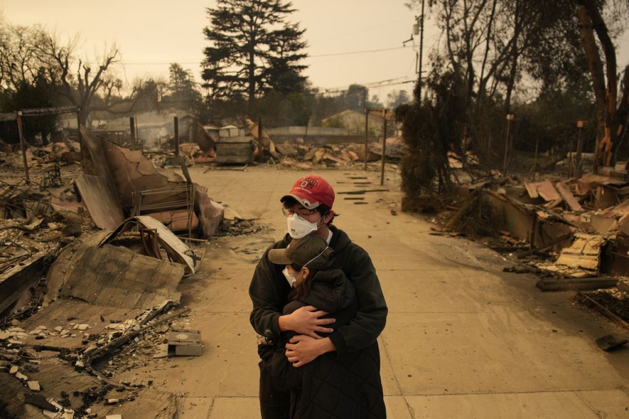 Ari Rivera, rear, Anderson Hao hold each other in front of their destroyed home in Altadena, Calif., Jan. 9, 2025. 