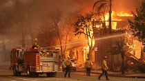 Firefighters hose down a burning structure on Lake Avenue  in the downtown Altadena section of Pasadena.