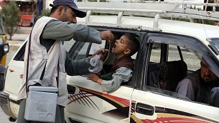 A health worker administers a polio vaccine to a child inside a taxi in the city of Jalalabad, Afghanistan, in October 2024.