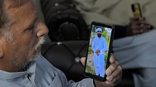 Mohammad Akram shows a photo of his son Abu Bakar who is feared to have drowned, on his cell phone at his home, in Jura village, Lalamusa district, Pakistan, Jan 17 2024
