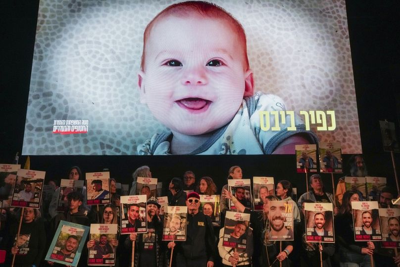 Demonstrators hold portraits of hostages held by Hamas in the Gaza Strip as a video featuring Kfir Bibas.