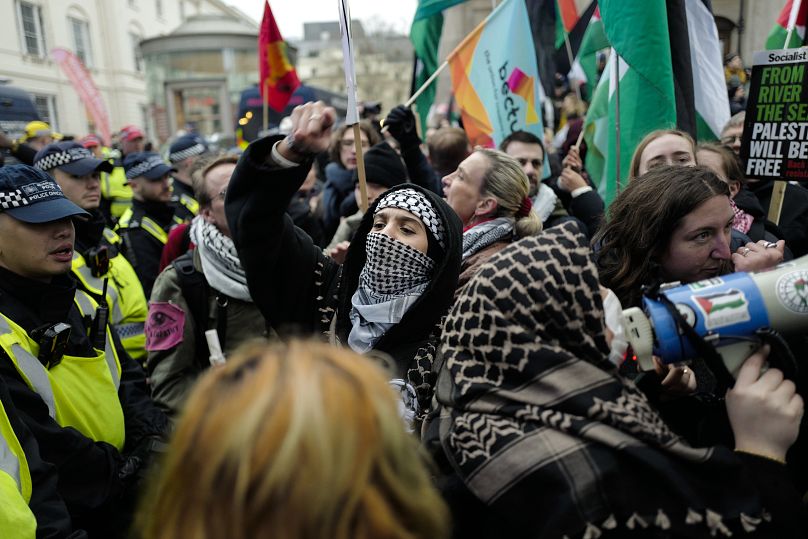 Londra'daki mitingde katılımcılar, bayrak ve dövizler taşıyor.