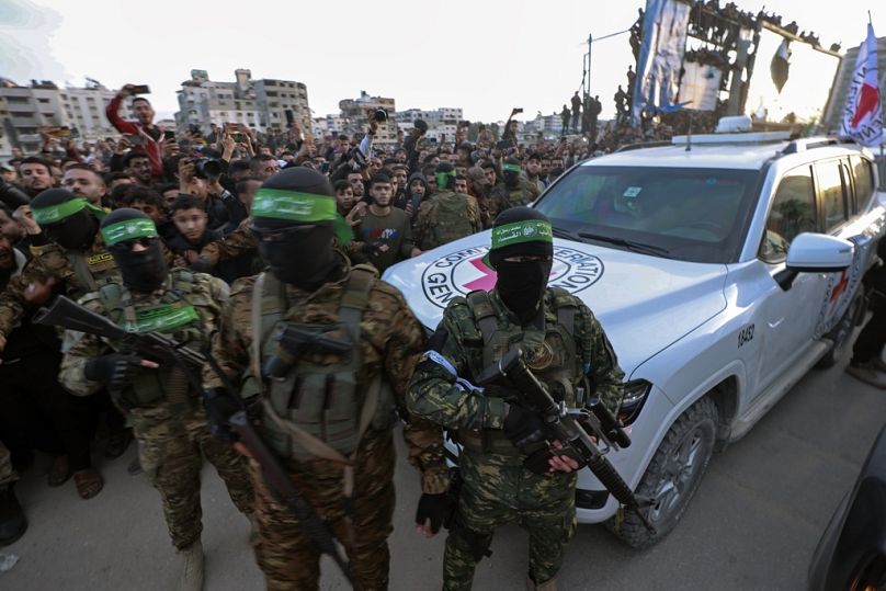 Hamas fighters escort a Red Cross vehicle to collect Israeli hostages released after a ceasefire agreement between Israel and Hamas took effect, in Gaza City, Jan. 19, 2025