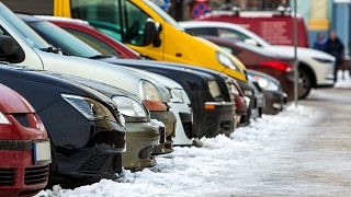 A row of parked cars on a snowy street. 