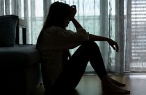 A woman sits with her head in her hands.