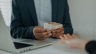 A man handing over euros to another person