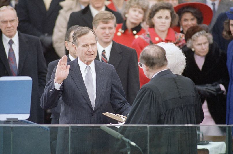 George Bush, left, raises his hand as he takes the oath of office as President of the United States outside the Capitol in Washington, Jan. 20, 1989