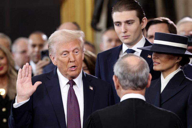 Donald Trump faz o juramento de posse enquanto Barron e Melania Trump assistem à 60ª cerimónia de tomada de posse presidencial na Rotunda do Capitólio dos EUA