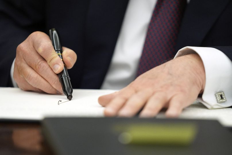 President Donald Trump signs executive orders in the Oval Office of the White House, Monday 20 January.