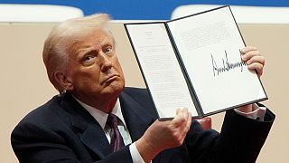 President Donald Trump holds up an executive order after signing it at an indoor Presidential Inauguration parade event in Washington, Monday, Jan. 20, 2025.