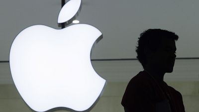 A person stands near the Apple logo at the company's new store in Grand Central Terminal, Wednesday, Dec. 7, 2011 in New York. 