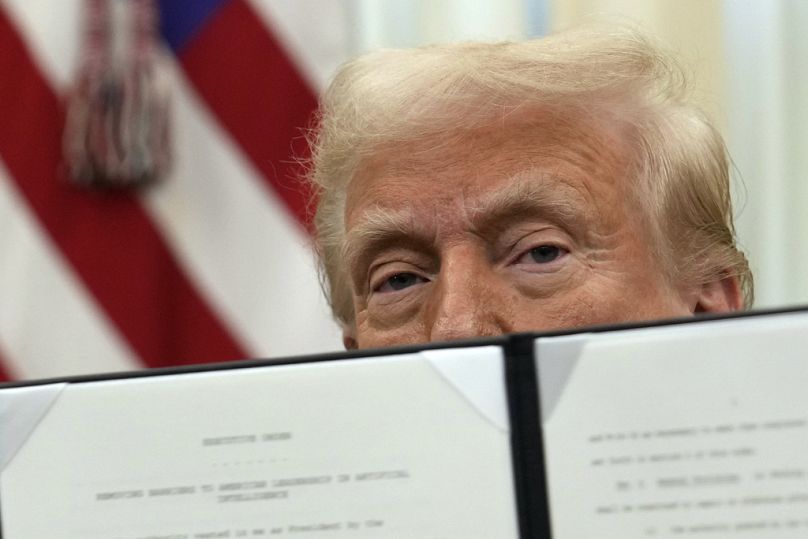 FILE: US President Donald Trump holds up a signed executive order in the Oval Office of the White House, Thursday, Jan. 23, 2025, in Washington.