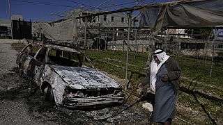  A Palestinian stands beside a torched car in the aftermath of an attack by suspected Israeli settlers in the West Bank village