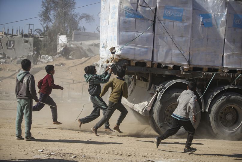 Palestinians chase humanitarian aid trucks that arrived through the Kerem Shalom crossing from Egypt