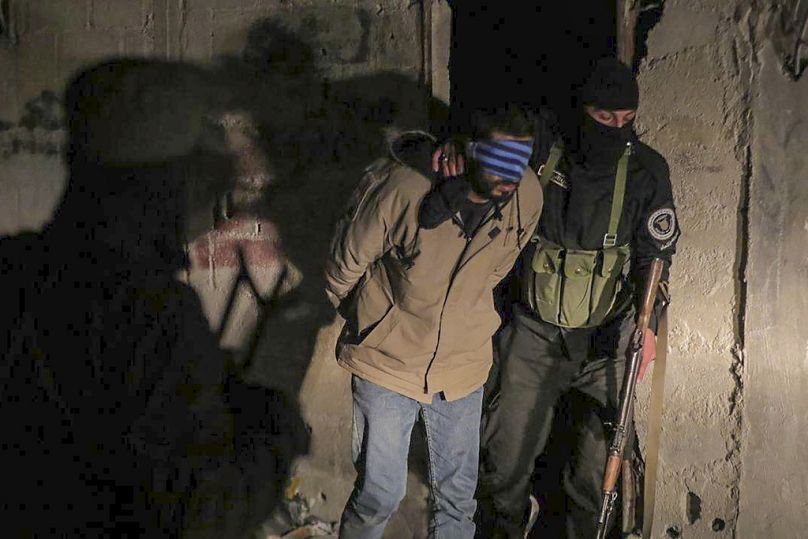 أحد المشتبه بهم  في التورط مع تنظيم ”داعش“ يرافقه ضباط الأمن في دمشق، سوريا، السبت، 11 يناير، 2025. 