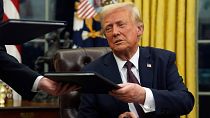 President Donald Trump signs executive orders in the Oval Office of the White House.