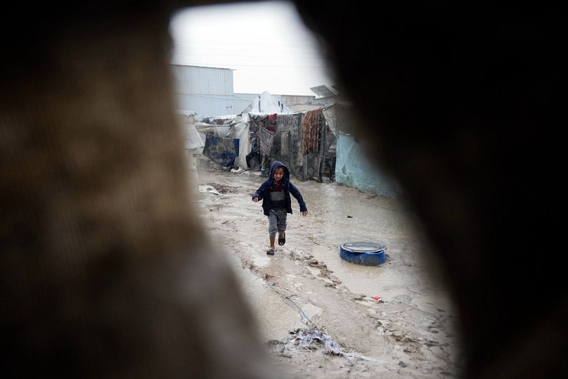 طفل يركض في شارع موحل بعد ليلة من الأمطار الغزيرة في دير البلح وسط قطاع غزة، الخميس 23 يناير/كانون الثاني 2025