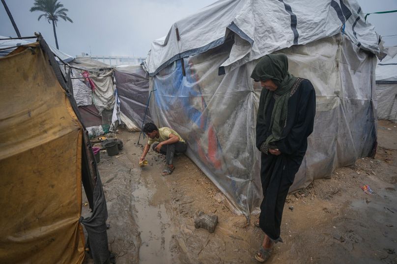 طارق ضيف الله يحاول إنشاء قناة بعلبة لتحويل المياه ومنعها من إغراق خيمته بعد ليلة من هطول الأمطار الغزيرة في دير البلح، وسط قطاع غزة، الخميس يناير/كانون الثاني. 23, 2025