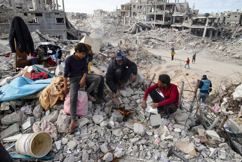 فلسطينيون نازحون يتجمعون حول نار بجوار منزلهم المدمر، بعد يوم من دخول اتفاق وقف إطلاق النار حيز التنفيذ، في رفح، قطاع غزة، الاثنين، 20 يناير 2025