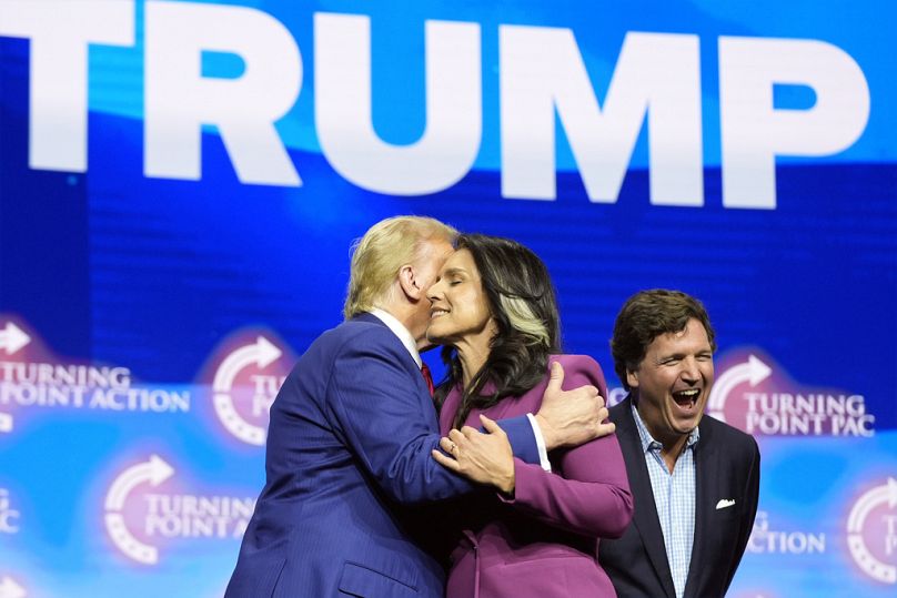 Tulsi Gabbard embraces Donald Trump alongside far-right pundit Tucker Carlson.