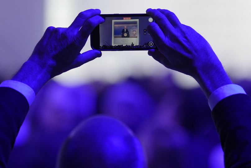  A man takes pictures during a virtual speech of U.S. president Donald Trump at the Annual Meeting of World Economic Forum in Davos, January 2025