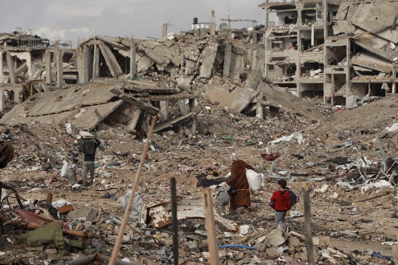 Palestinians walk on the rubble of destroyed houses, after the ceasefire deal between Israel and Hamas, in Gaza City, Gaza Strip, Friday, Jan. 24, 2025. (AP Photo/Abed Hajjar)