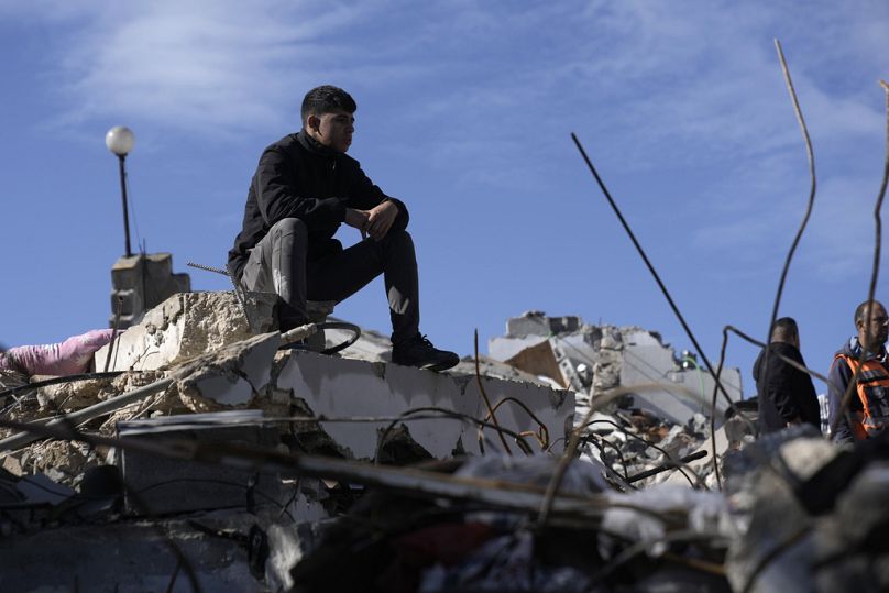 A Palestinian sits on the rubble at the site where Israeli forces killed two Palestinian militants who carried out a deadly attack on a bus in the West Bank earlier this month