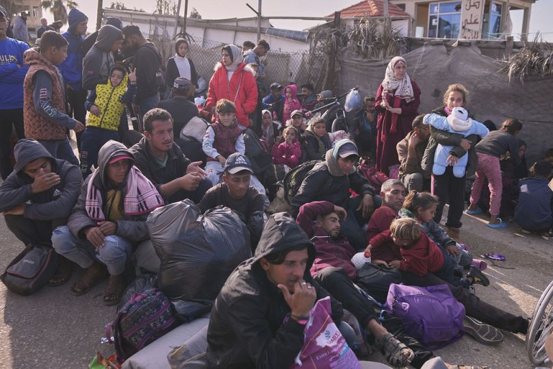 Palestinians wait next to their belongings in central Gaza, Saturday, Jan. 25, 2025, as the Israeli military is warning Palestinians not to return to northern Gaza