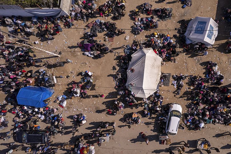 Palestinos desplazados se reúnen con sus pertenencias cerca de un control de carretera mientras esperan poder regresar a sus hogares en el norte de la Franja de Gaza.