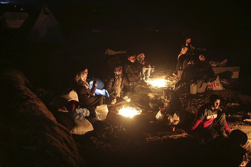 Palestinos desplazados se reúnen con sus pertenencias cerca de un control de carretera mientras esperan poder regresar a sus hogares en el norte de la Franja de Gaza.