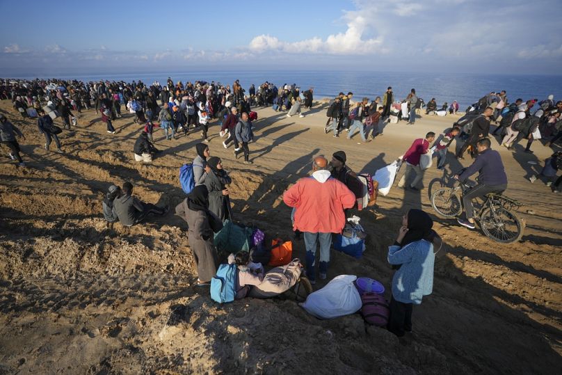 عائلة فلسطينية تستريح أثناء عودتها إلى شمال القطاع  الاثنين، 27 يناير/كانون الثاني 2025.
