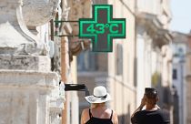 A man takes a photo of the temperature of 43C recorded in the sun outside a pharmacy in downtown Rome.