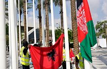 Flag of Albania, left, and the old flag of Afghanistan, are adjusted ahead of the COP28 U.N. Climate Summit, Wednesday, Nov. 29, 2023, in Dubai, United Arab Emirates.