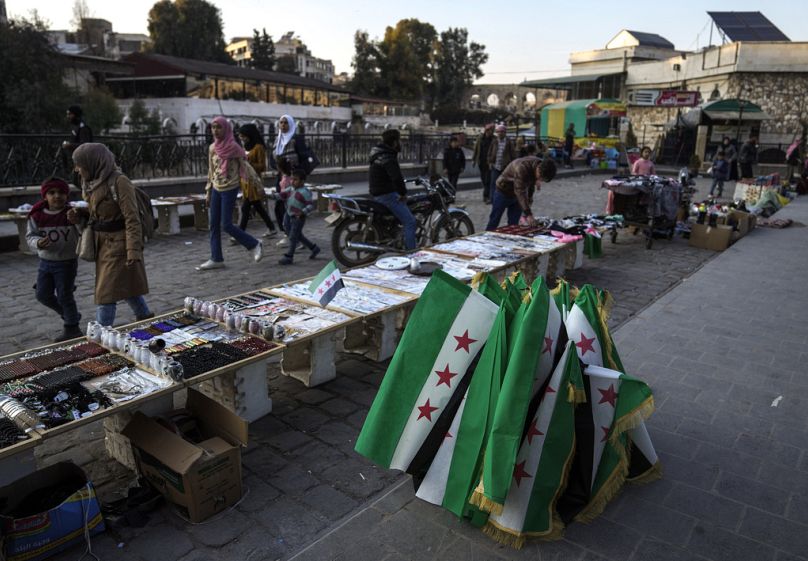 People pass by street vendors displaying goods for sale in the main square of Hama, January 2025