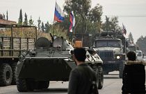 FILE - Syrian fighters watch Russian armoured vehicles driving past near the Hmeimim Air Base, a Syrian airbase currently operated by Russia, 16 December 2024. 