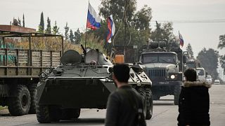 FILE - Syrian fighters watch Russian armoured vehicles driving past near the Hmeimim Air Base, a Syrian airbase currently operated by Russia, 16 December 2024. 