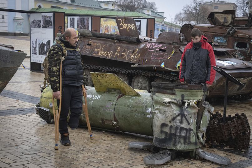 FILE: A war veteran, who lost his leg in the Russia-Ukraine war, and his son look at fragments of the Russian rocket at an exhibition in central Kyiv, Ukraine, Jan. 10, 2025 