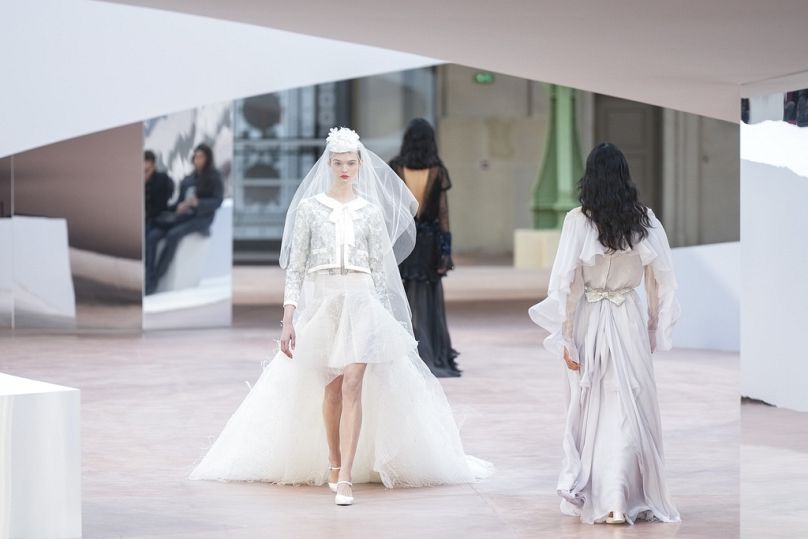 A model graces the runway in a bridal-inspired creation from Chanel's Haute Couture Spring/Summer 2025 collection.