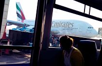 A woman in a bus looks out at an Emirates Airbus A380 jumbo jet at Dubai International Airport in Dubai, United Arab Emirates, Friday, Sept. 9, 2022. 
