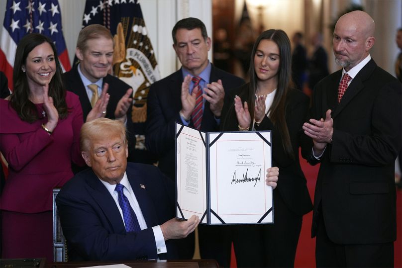 President Donald Trump holds the document after signing the Laken Riley Act during an event in the East Room of the White House. 