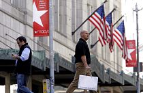 Shoppers walk past a Macy's store - FILE PHOTO