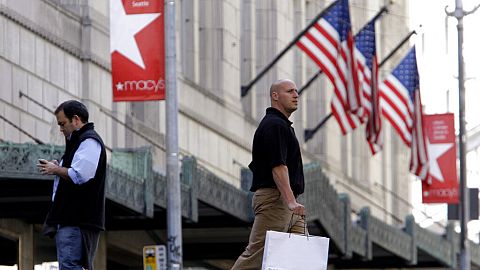 Shoppers walk past a Macy's store - FILE PHOTO