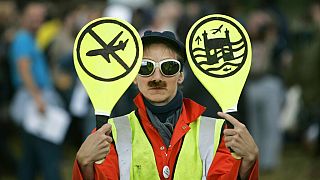 An environmental activist imitates an airport worker near London's Heathrow Airport
