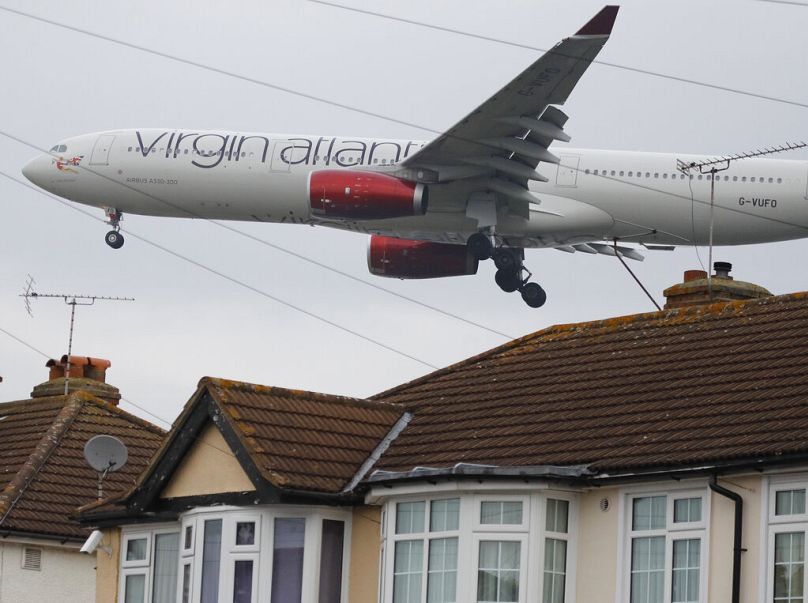 A Virgin Atlantic plane on final approach to landing skims over the rooftops of nearby houses at Heathrow Airport in London