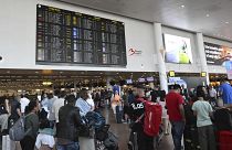 Travelers wait for information in front of a departure board at Brussels International Airport in Brussels, 19 July, 2024